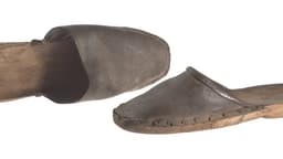 A photograph of two 19th-century wooden clog shoes