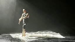 Russell dancing on a white tarp with grated lighting